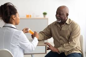 Farmacêutica explicando a prescrição ao paciente durante o atendimento clínico, indicando a forma correta de uso do medicamento.