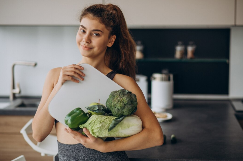 Mulher segurando vegetais frescos, simbolizando alimentação natural