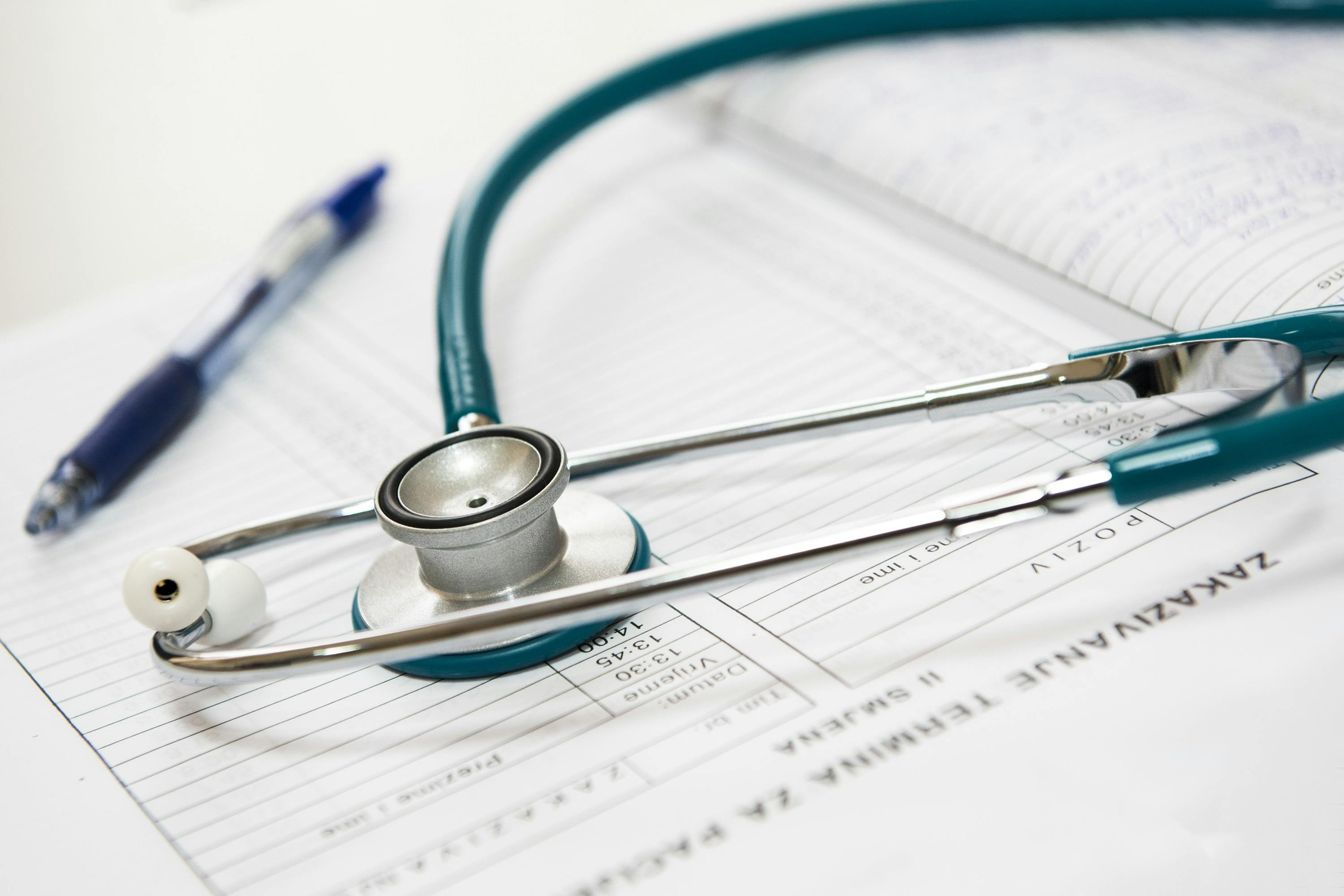 Estetoscópio e caneta sobre prontuário médico, simbolizando o cuidado com a saúde, diagnóstico preciso e a prática da medicina