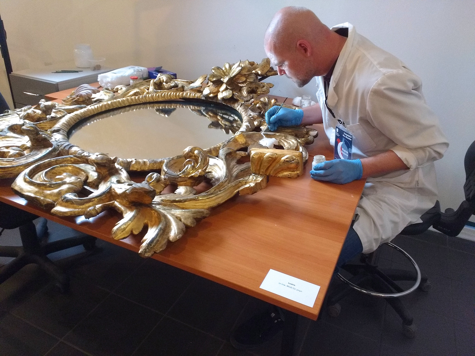Profissional trabalhando na restauração detalhada de uma obra de arte com instrumentos específicos