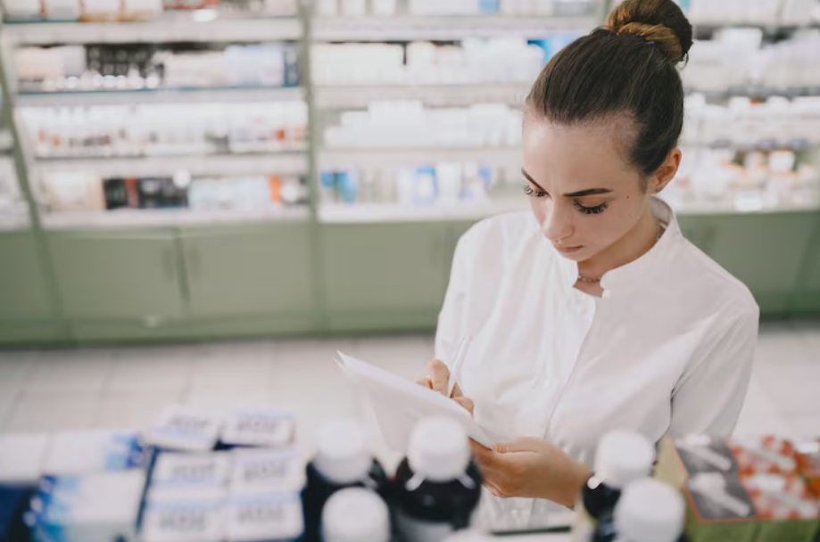 Profissional farmacêutica confere dados de prescrição em balcão de dispensação