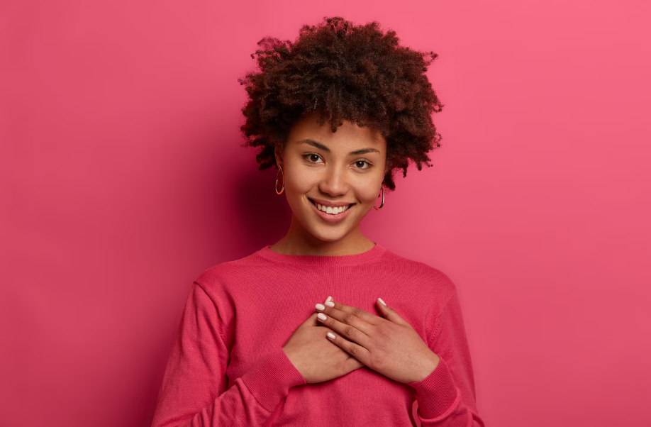 Mulher com laço rosa no peito em apoio ao Outubro Rosa