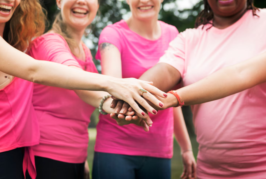 Grupo de mulheres vestindo rosa com as mãos unidas em apoio à campanha