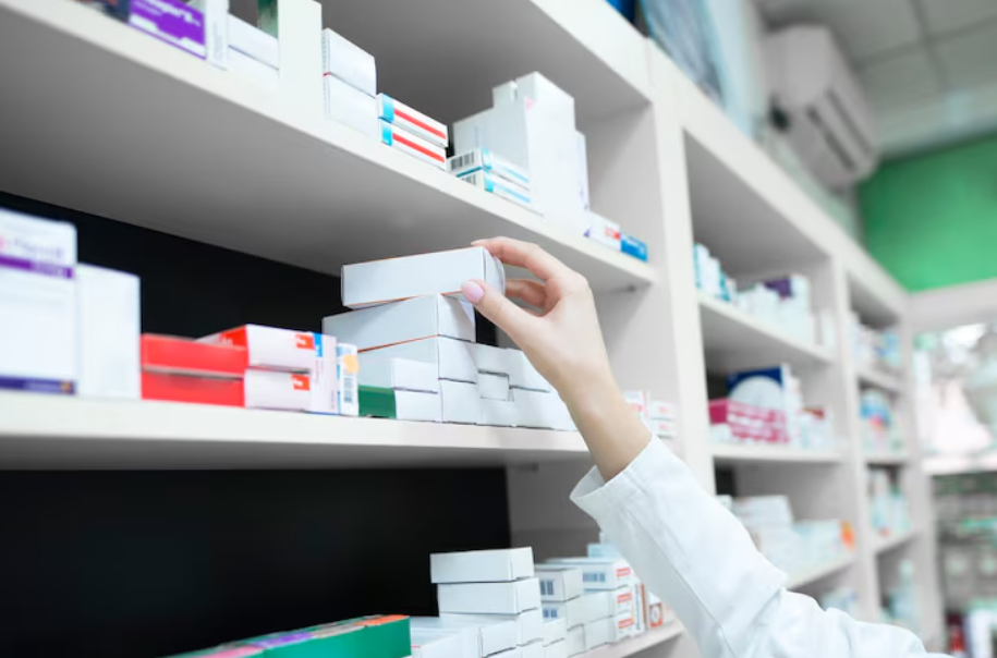 Profissional organizando medicamentos em prateleiras de farmácia