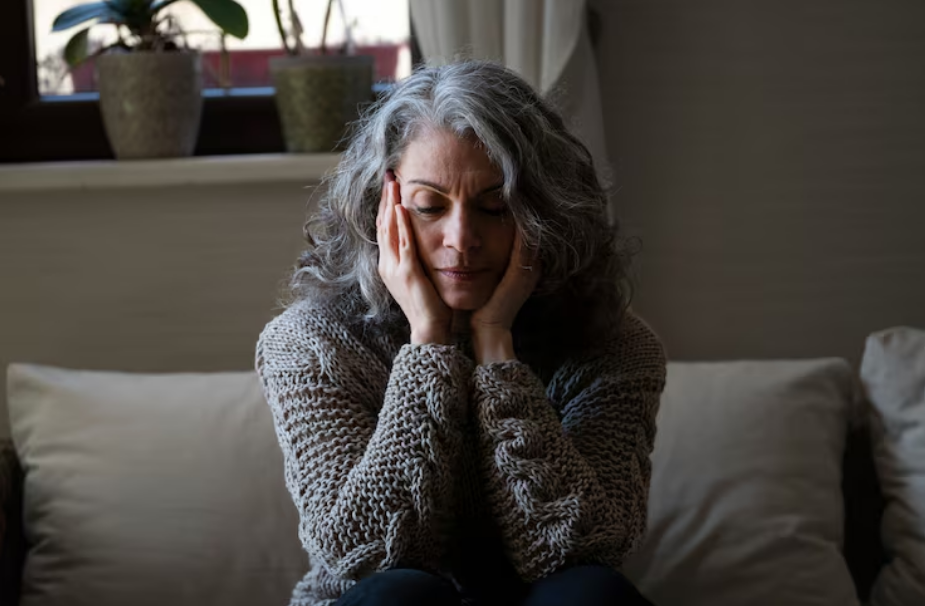 Idosa sentada no sofá com expressão triste, reforçando a observação clínica