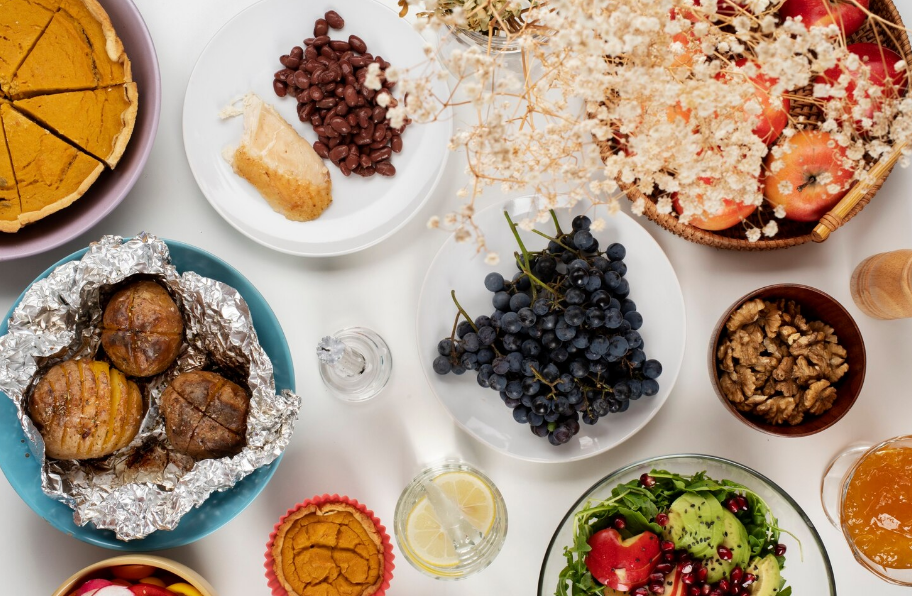 Mesa com pratos variados de frutas, legumes, carnes e sobremesas com separação de categorias